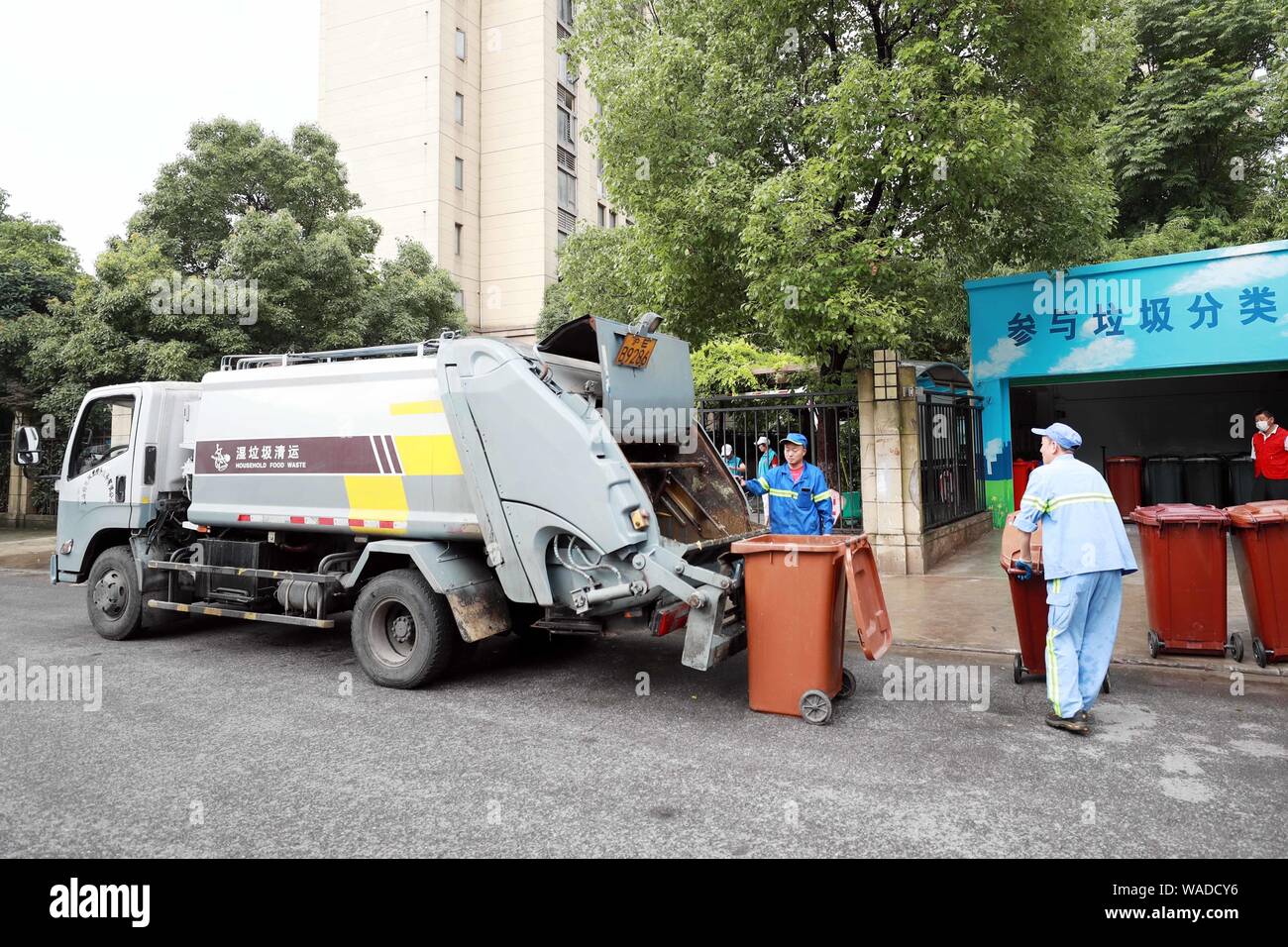 Lavoratori cinesi mettere contenitori di uso domestico rifiuti alimentari in un camion della spazzatura di fronte a una zona residenziale in Cina a Shanghai, 30 giugno 2019. Rifiuti domestici Foto Stock