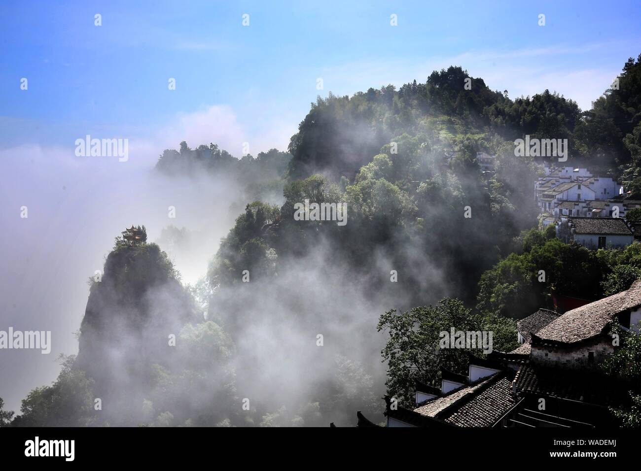 Viste indistict Hui-edifici di stile in parte nascosta e parzialmente visibile nelle nebbiose montagne Qiyun in montagna, Xiuning county, Huangshan city, est Foto Stock