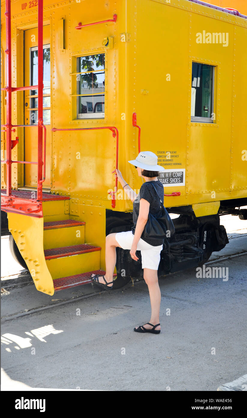 Sacramento. La donna indossa pantaloncini e un cappello da sole a bordo di una cabinovia gialla nella Citta' Vecchia di Sacramento. Foto Stock