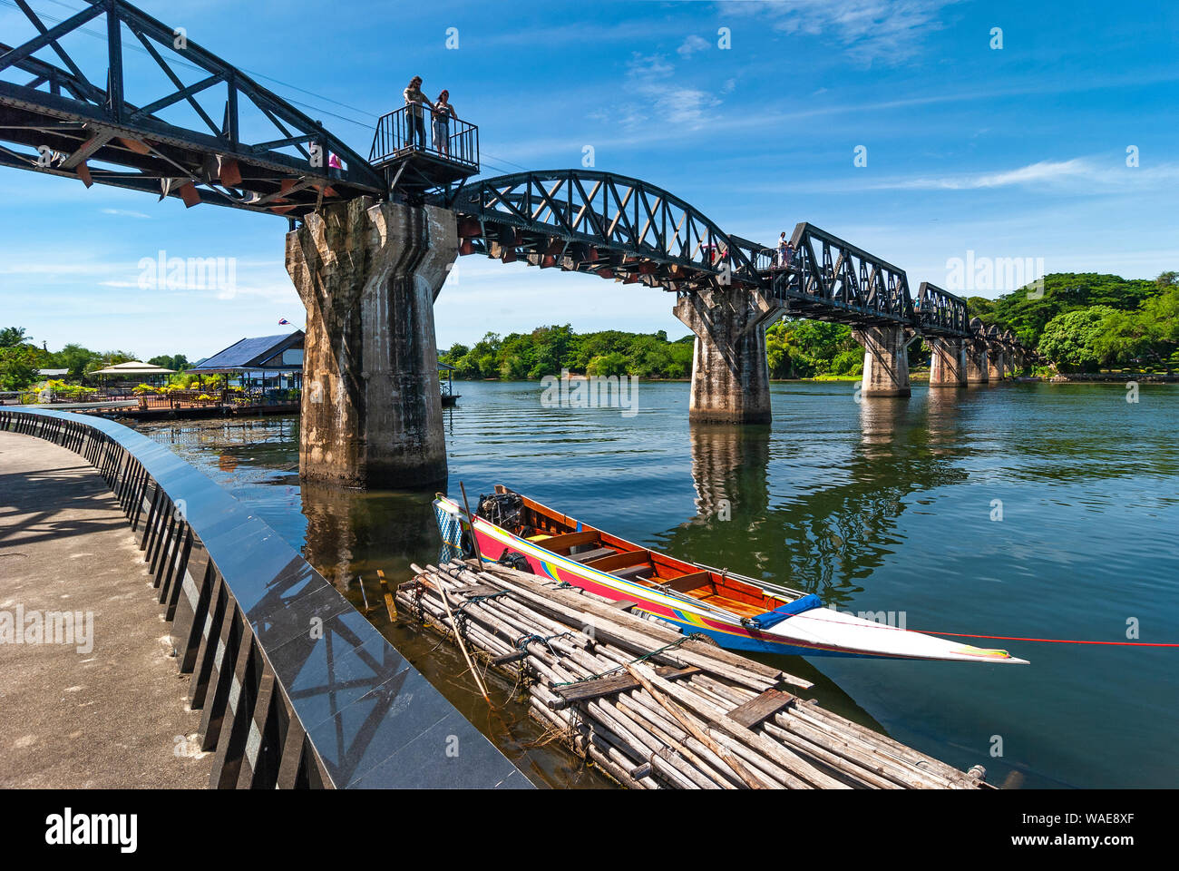 Due turisti che guarda sul fiume Kwai dal ponte sul fiume Kwai (ferrovia della morte in guerra mondiale 2) con una barca veloce, Kanchanaburi, Thailandia. Foto Stock