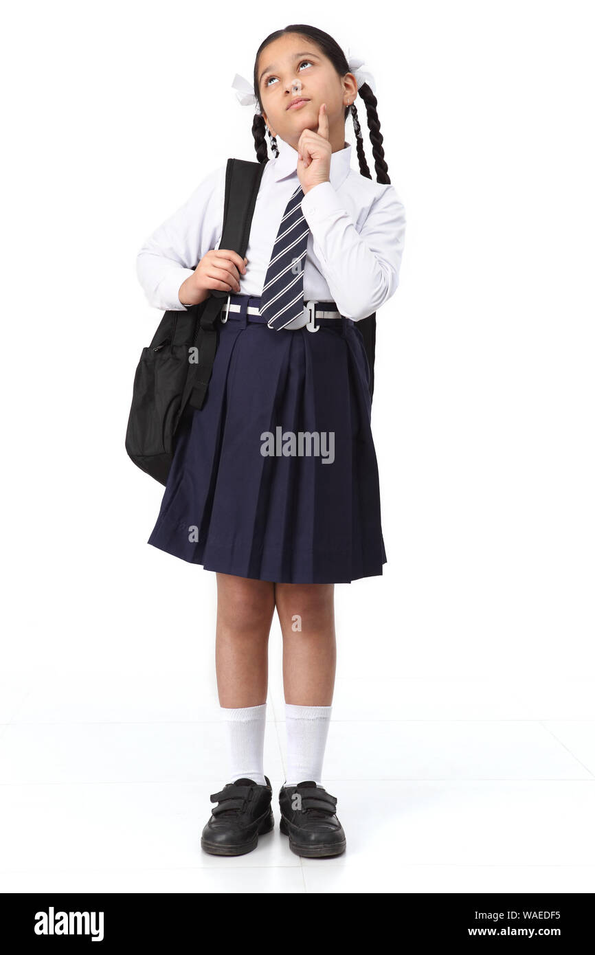 Schoolgirl in piedi con zaino e pensare Foto Stock