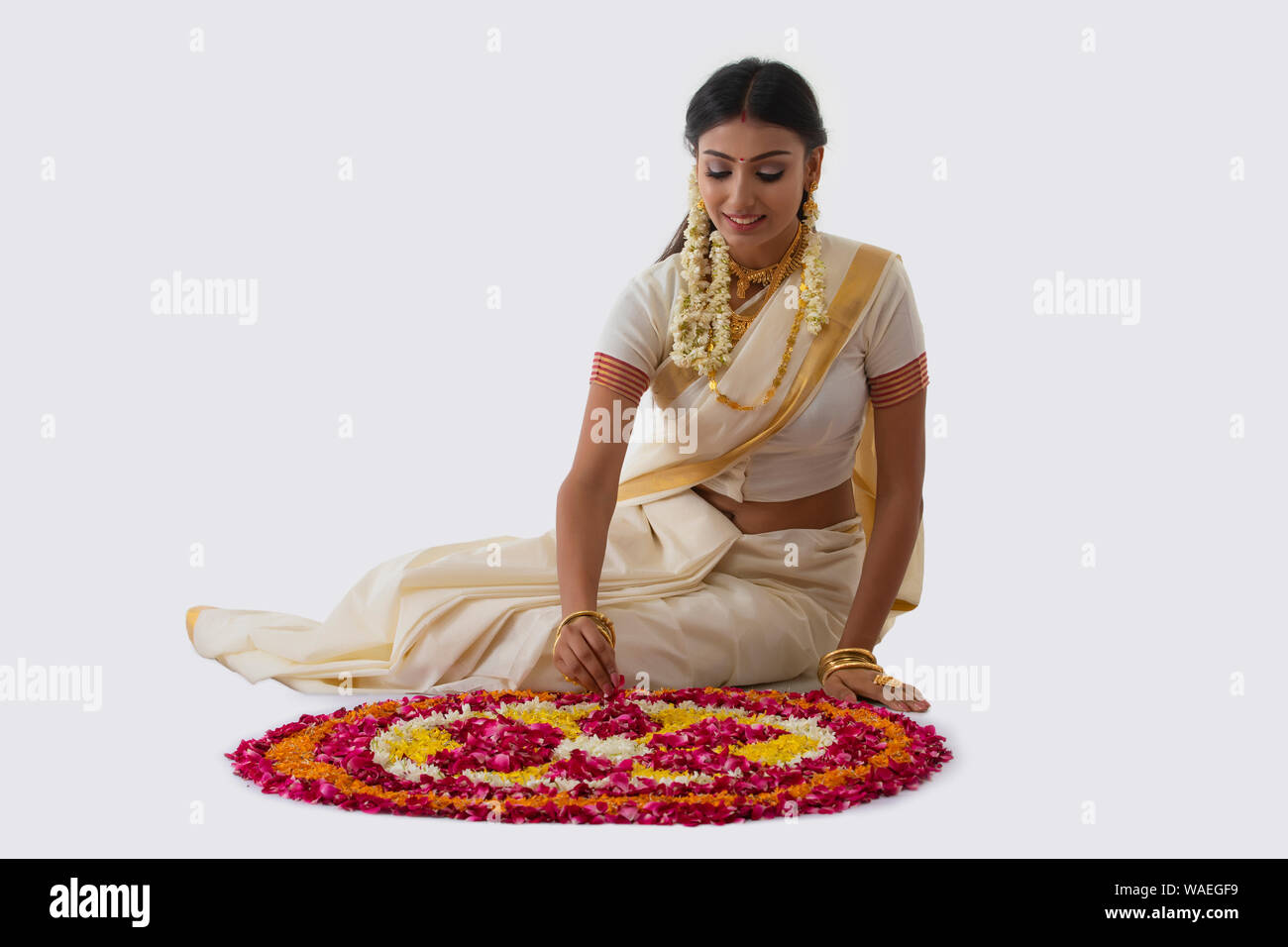 Bella donna rendendo rangoli con fiori su onam Foto Stock