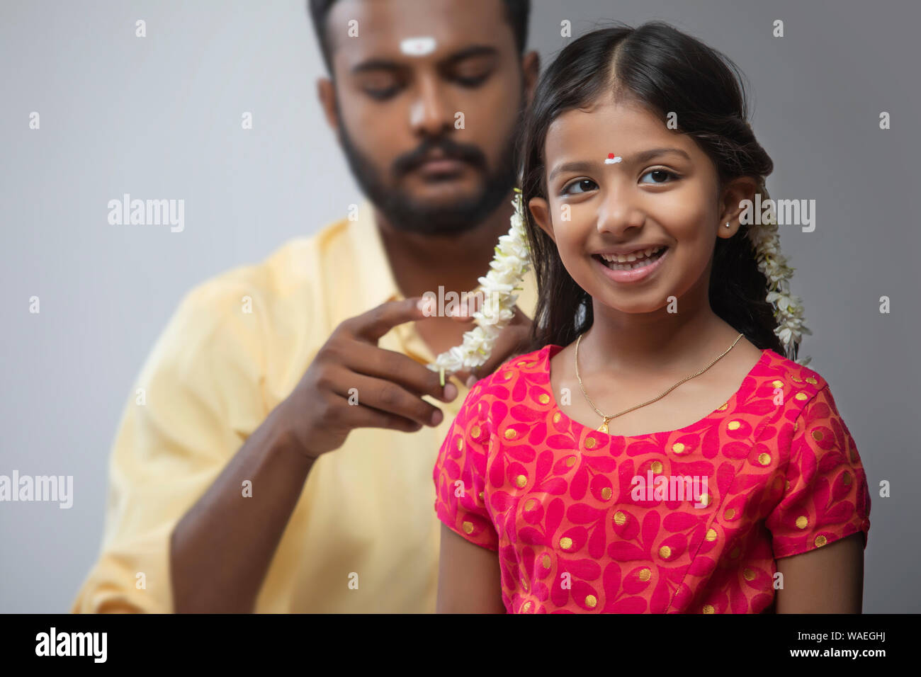 Sud indiane uomo mettendo gajra nelle sue figlie capelli Foto Stock