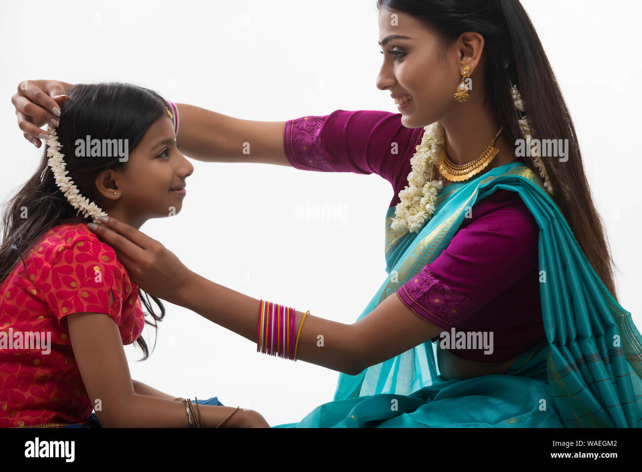 Sud donna indiana mettendo gajra nelle sue figlie capelli Foto Stock