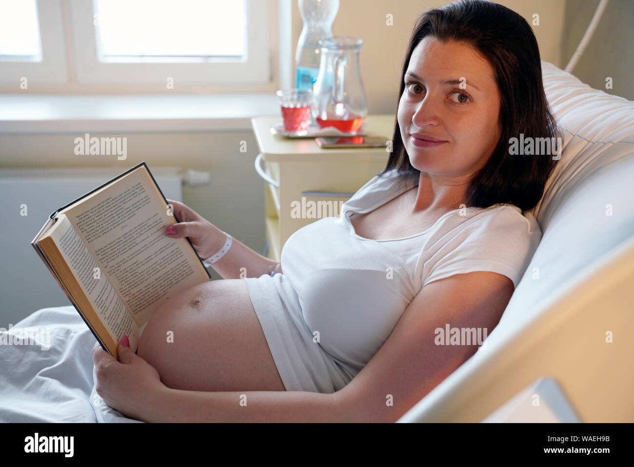 Ad alto rischio di gravidanza, donna incinta con libro nel letto di ospedale, Carlsbad, Repubblica Ceca Foto Stock