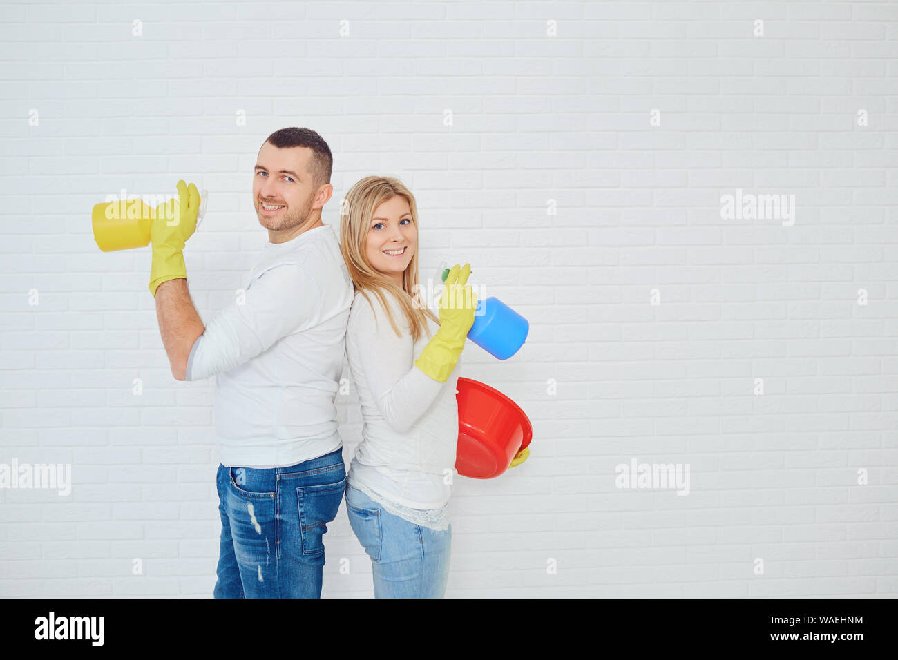 Famiglia giovane condivisione domestiche di pulizia su sfondo bianco. Foto Stock