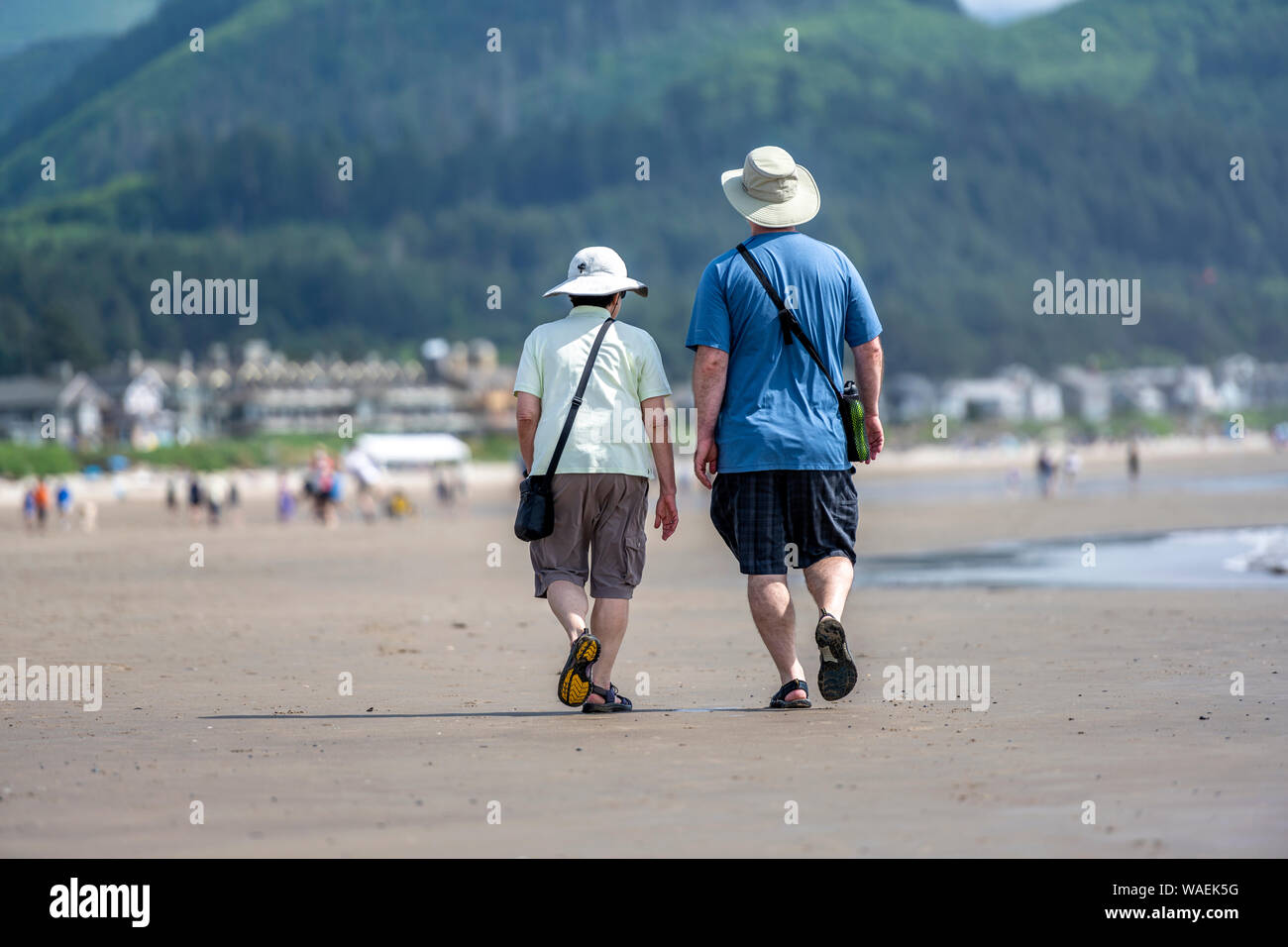 Tozza coppia di anziani in panamas stanno camminando lungo la riva del nord-ovest Oceano Pacifico e respirando la salutare aria fresca di mare per rafforzare l'immunità Foto Stock