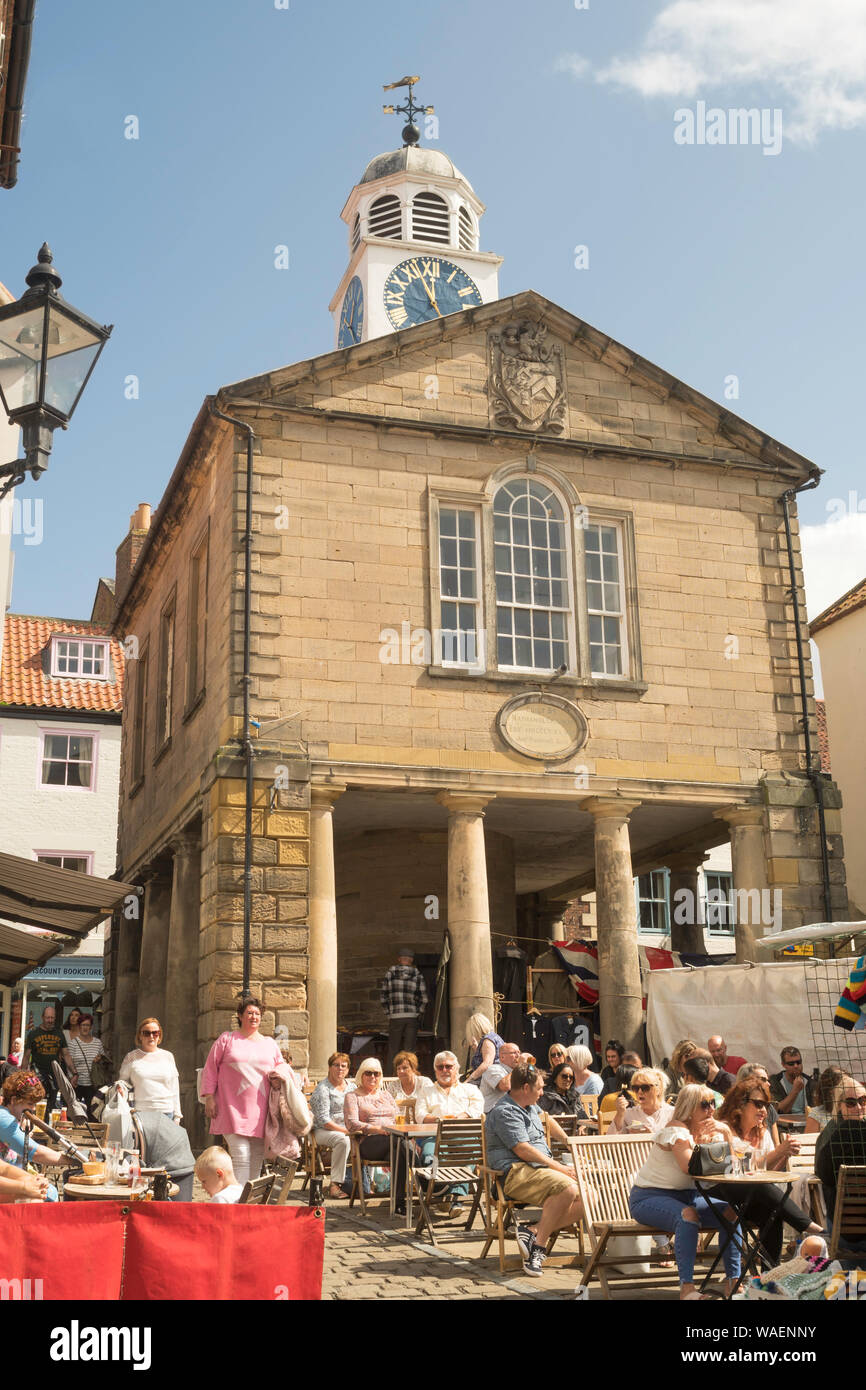 Persone mangiare a un cafe' all'aperto a Whitby market place, North Yorkshire, Inghilterra, Regno Unito Foto Stock