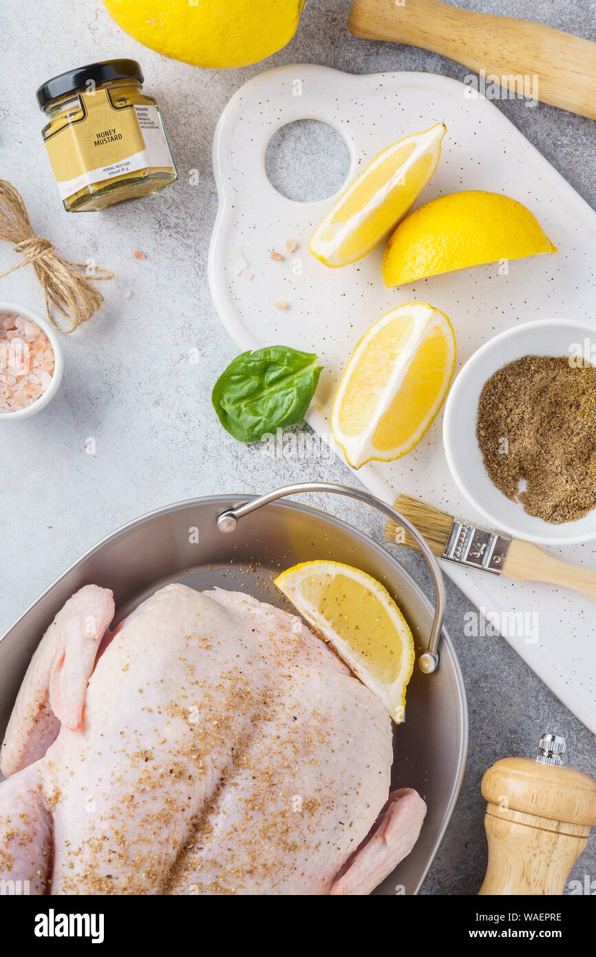 La preparazione di ripieni tacchino intero o di pollo per una celebrazione festosa cena. Il pollo crudo con erbe aromatiche, spezie, succo di limone e il miele della senape. Foto Stock