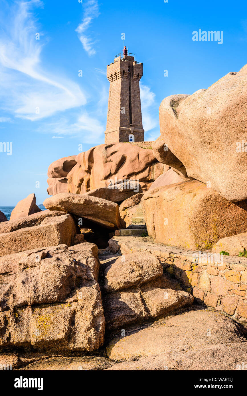 Il Ploumanac'h faro, denominato significa Ruz, sulla Costa di Granito Rosa in Perros-Guirec, nel nord della Bretagna, con massi di granito in primo piano. Foto Stock