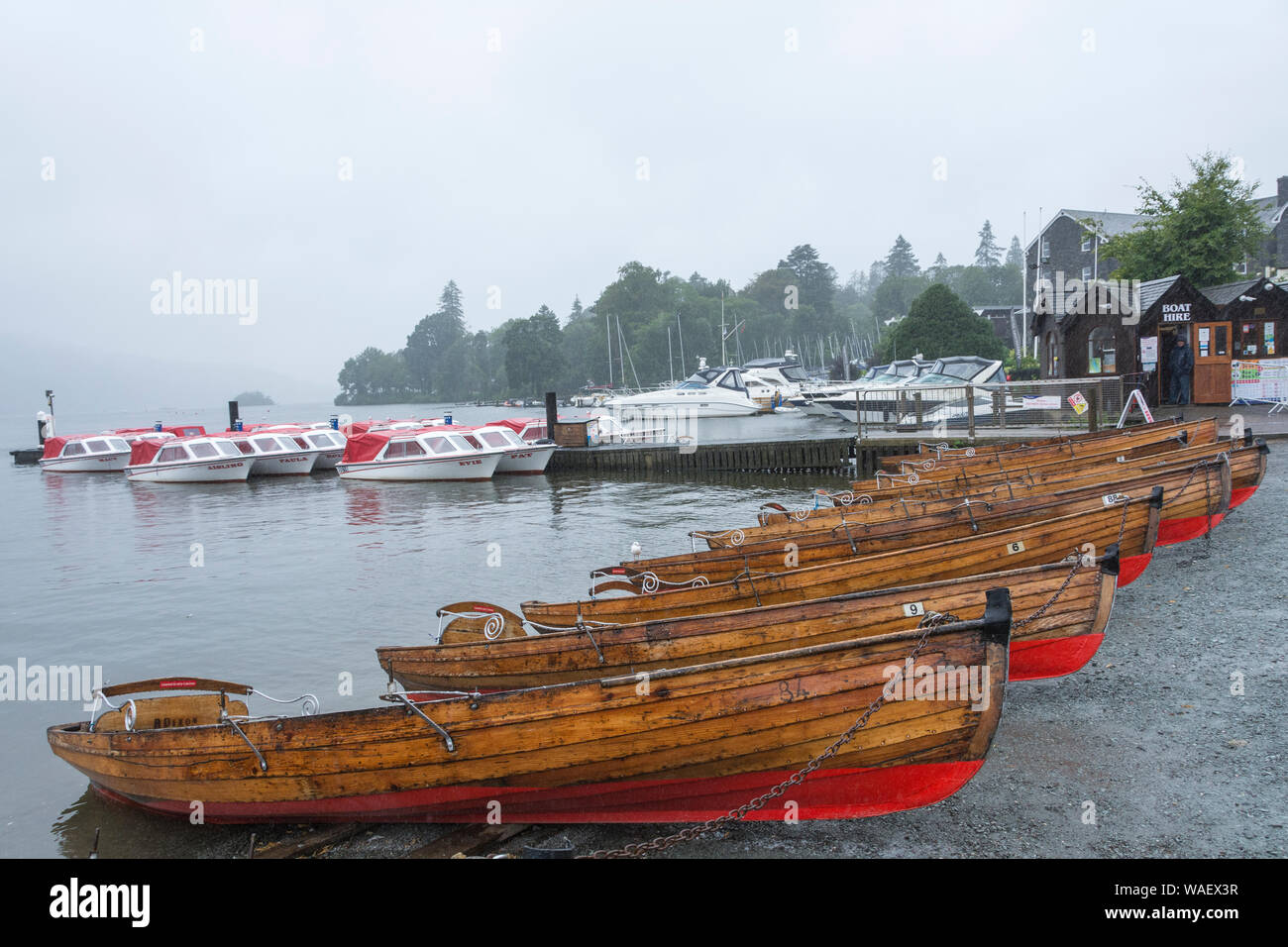 Le tradizionali barche a remi a noleggio in un giorno di pioggia accanto al lago di Windermere, Lake District, Cumbria, Regno Unito Foto Stock