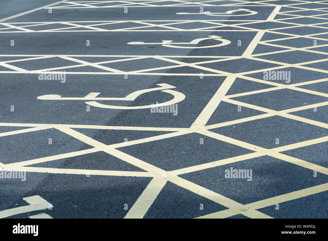 Primo piano della Blue Badge simbolo di sedie a rotelle e parcheggio disabili Segnaletica in una baia di parcheggio Foto Stock