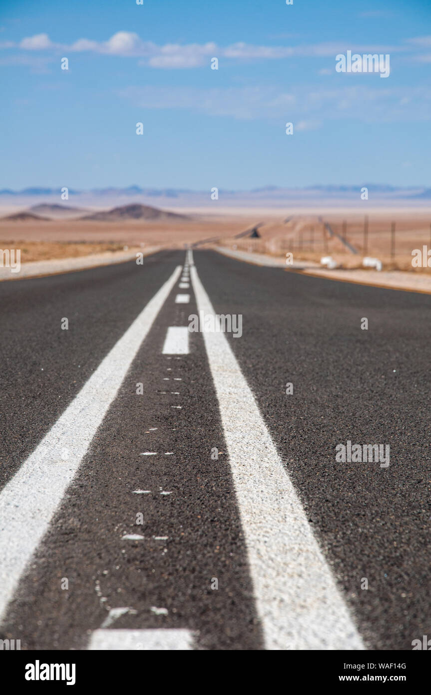 Un tratto di strada asfaltata attraversando parte del deserto del Namib Foto Stock