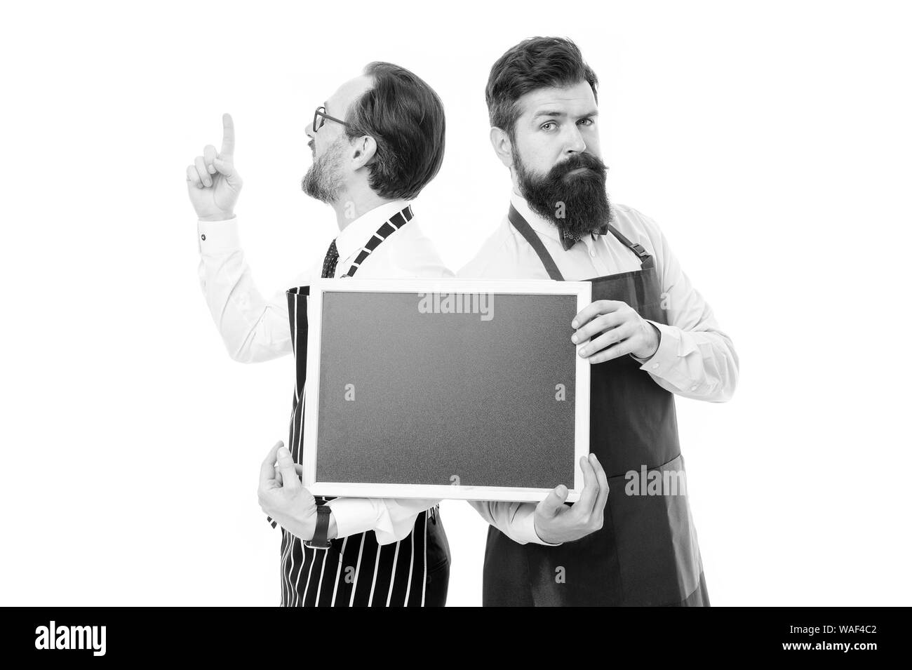 Gli uomini barbuti barista in attesa della catenaria lavagna vuota. Barista con blackboard annuncio. Hipster barista visualizza blackboard copia spazio. Assunzione di personale del ristorante. Gli uomini barbuti informare le ore felici. Foto Stock
