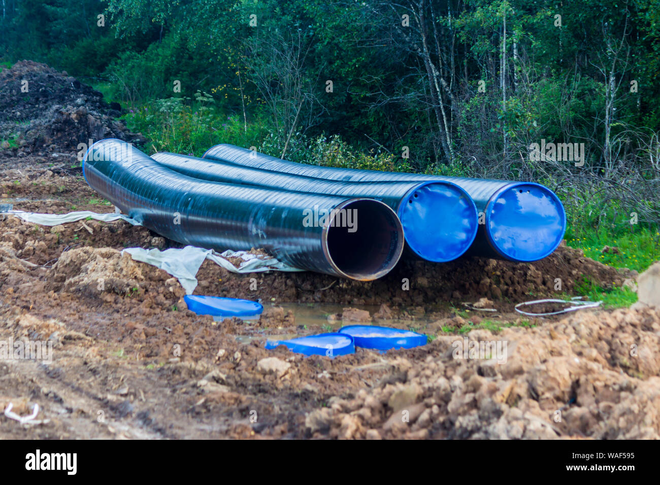 La ricostruzione del gasdotto . I nuovi tubi pronti per l'installazione. La Taiga come sfondo. Il terreno scavato e tracce di attrezzature di costruzione . Foto Stock