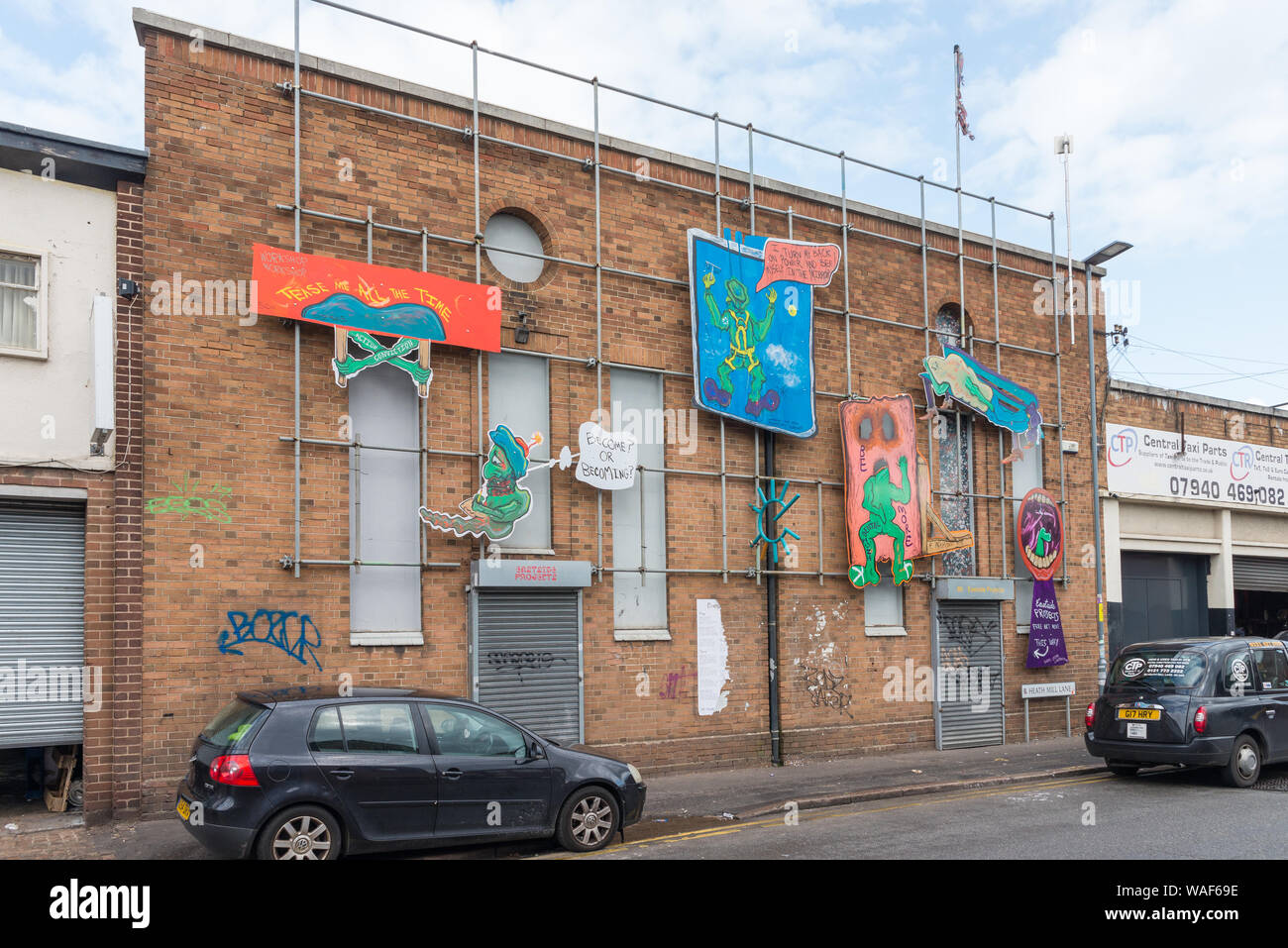 Piccolo edificio in Digbeth, Birmingham coperta da impalcature e sollevata opera d'arte in stile cartoon Foto Stock