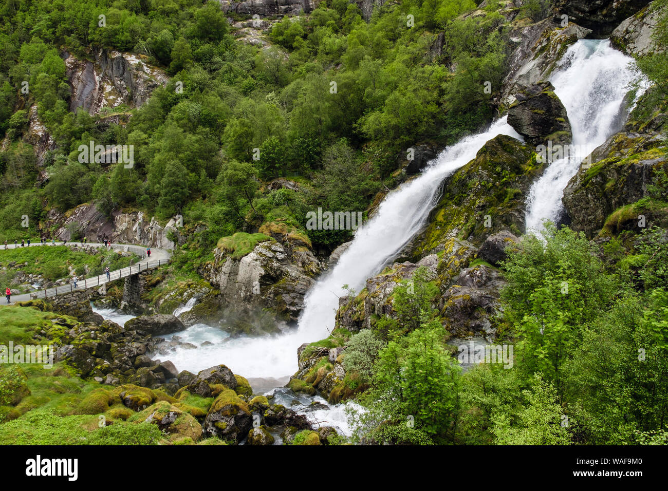 Cascata sopra il sentiero turistico itinerario con i turisti a piedi nella Briksdalen o Briks valley, Stryn, Sogn og Fjordane county, Norvegia e Scandinavia Foto Stock