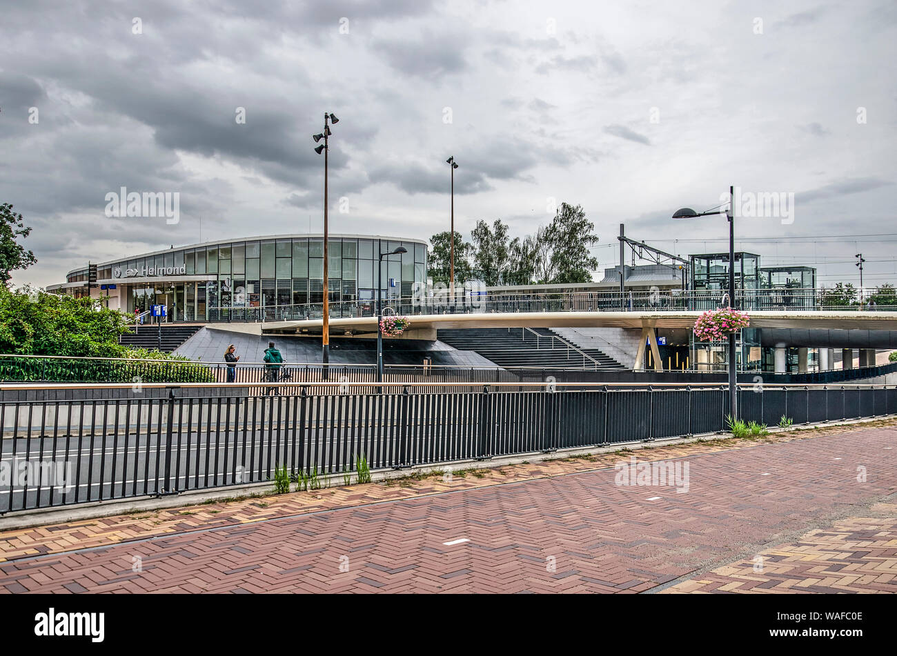 Helmond, Paesi Bassi, 16 agosto 2019: un ponte per biciclette e pedoni attraversa una strada trafficata su piazzale della stazione con la nuova ferrovia stazio Foto Stock
