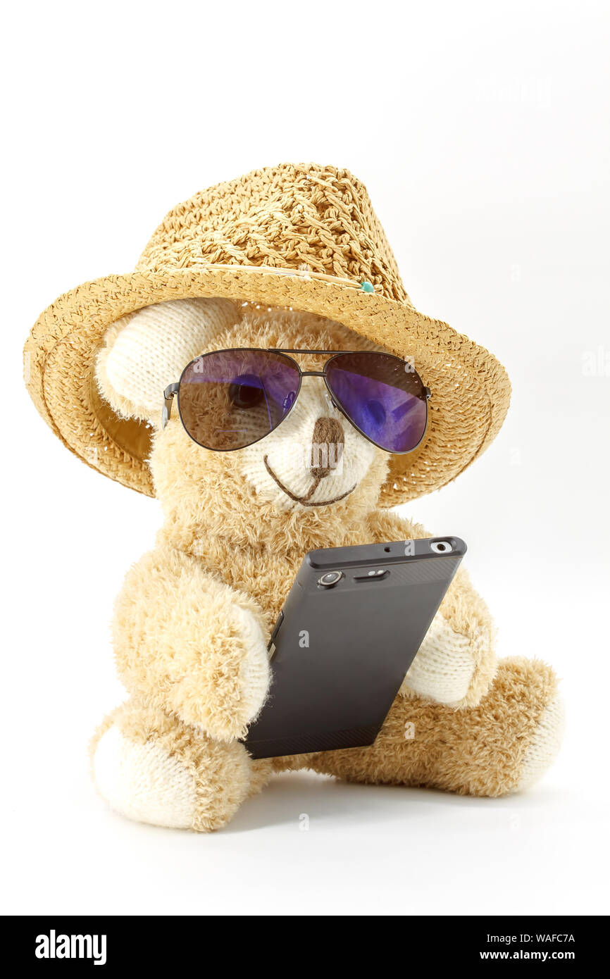 Orsacchiotto di peluche con gli occhiali e lo smartphone su sfondo bianco Foto Stock