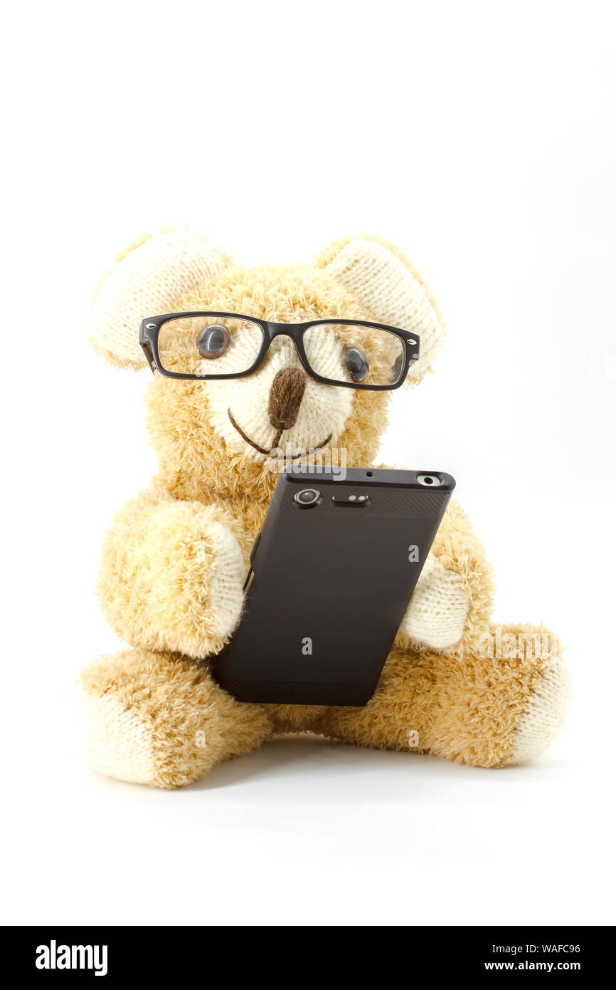 Orsacchiotto di peluche con gli occhiali e lo smartphone su sfondo bianco Foto Stock