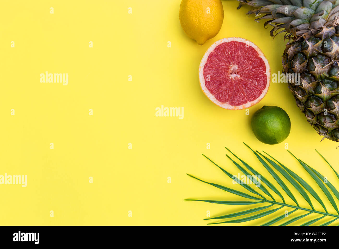 La frutta tropicale con foglie di piante di ananas pompelmo cibo minimo estate le foglie di piante di colore giallo brillante colore di sfondo Foto Stock