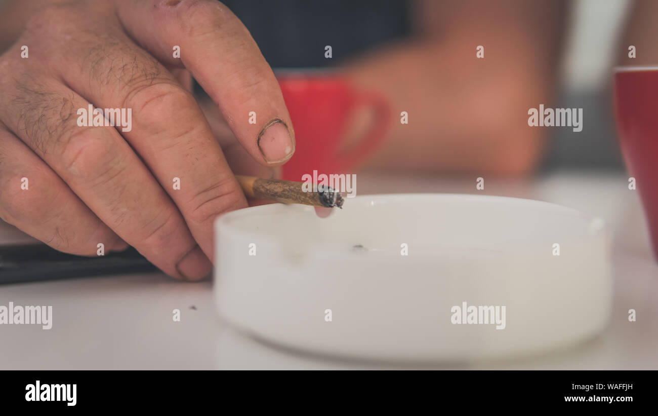La marijuana medica in comune la mano, close-up. Fumare cannabis blunt in ambienti chiusi. La canapa è un concetto di medicina a base di erbe Foto Stock