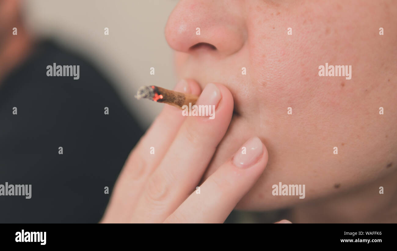 La marijuana medica in comune la mano, close-up. Fumare cannabis blunt in ambienti chiusi. La canapa è un concetto di medicina a base di erbe Foto Stock