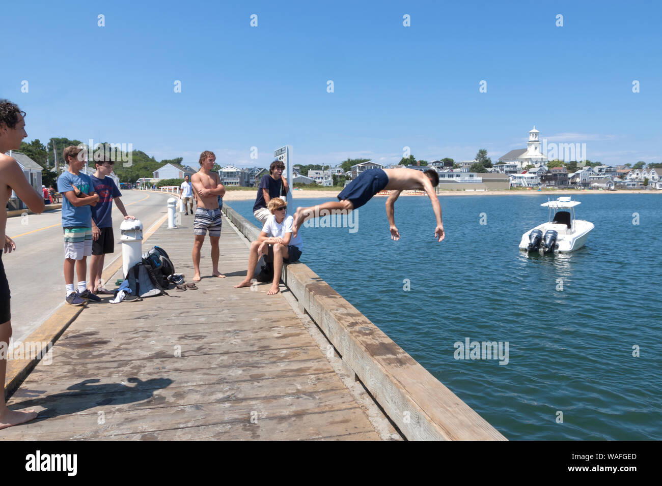 Ragazzo adolescente immersioni subacquee pier in acqua come il suo gruppo di amici guardare. Foto Stock