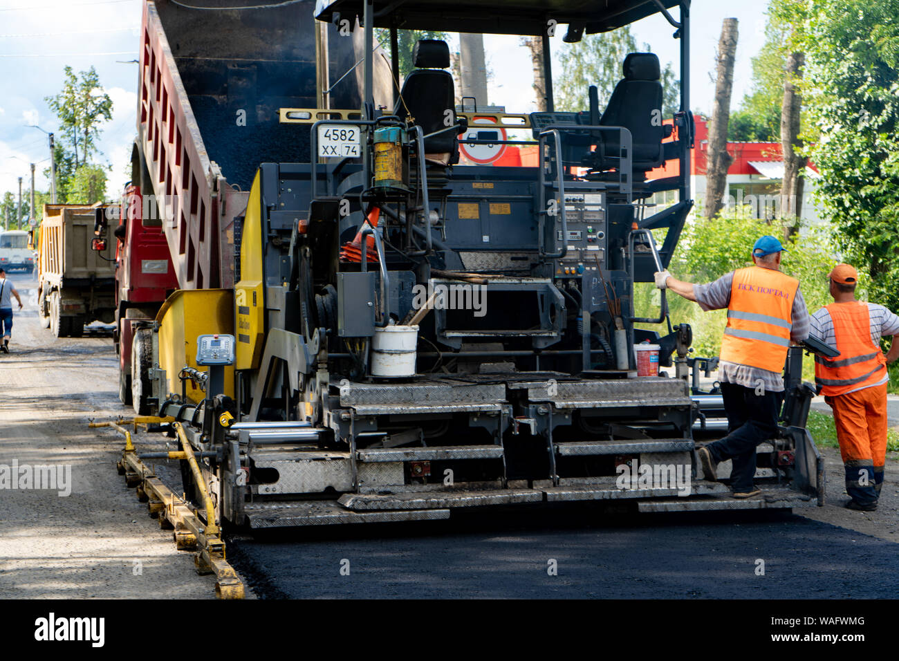 La regione di Celjabinsk, Russia - Agosto 2019. Nuovo lastricatore in azione. Riparazione su strada. Asfalto da pavimentazione. La posa di un nuovo strato di asfalto Foto Stock