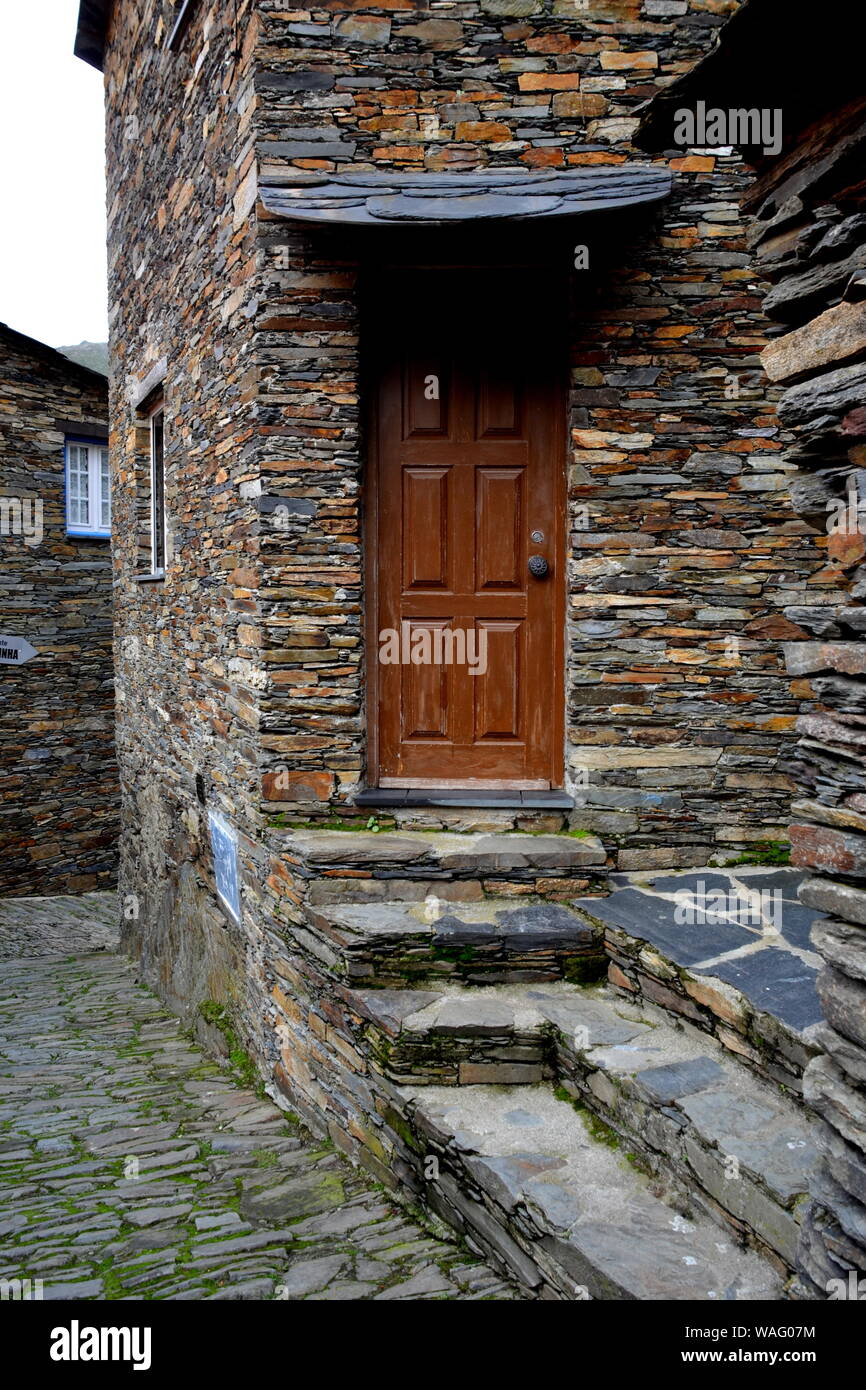 Rustico mano-scavato nella porta di legno inserito in una parete di pietra costruito da scisto in Piodão, fatta di rocce argillose stack, uno del Portogallo villaggi scisti nell'ALDE Foto Stock