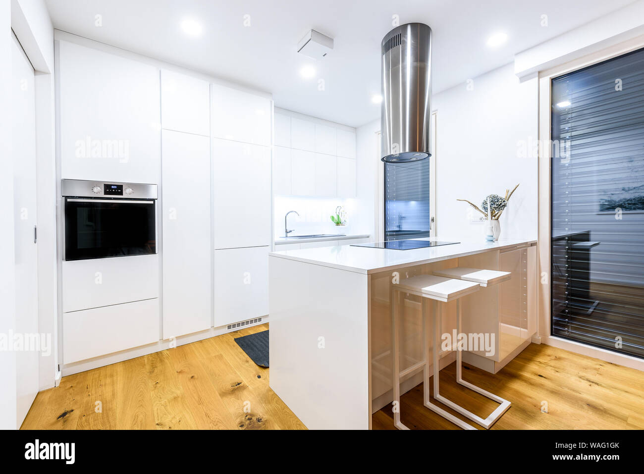 Interior design nuovo bianca e moderna cucina con elettrodomestici per la cucina. Luxury cucina residenziale con lavandino, fornello, piano di cottura e del bianco armadi in legno e disco Foto Stock