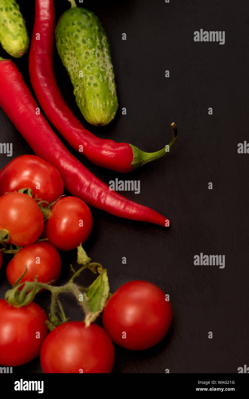 Pomodori maturi e cetrioli su sfondo nero Foto Stock