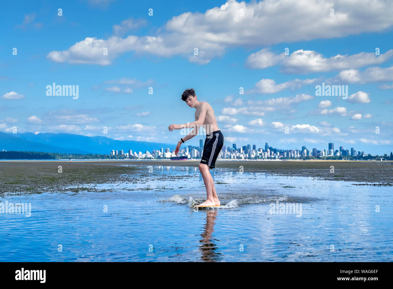 Ragazzo adolescente skimboarding, banche spagnole, English Bay, Vancouver, British Columbia, Canada Foto Stock