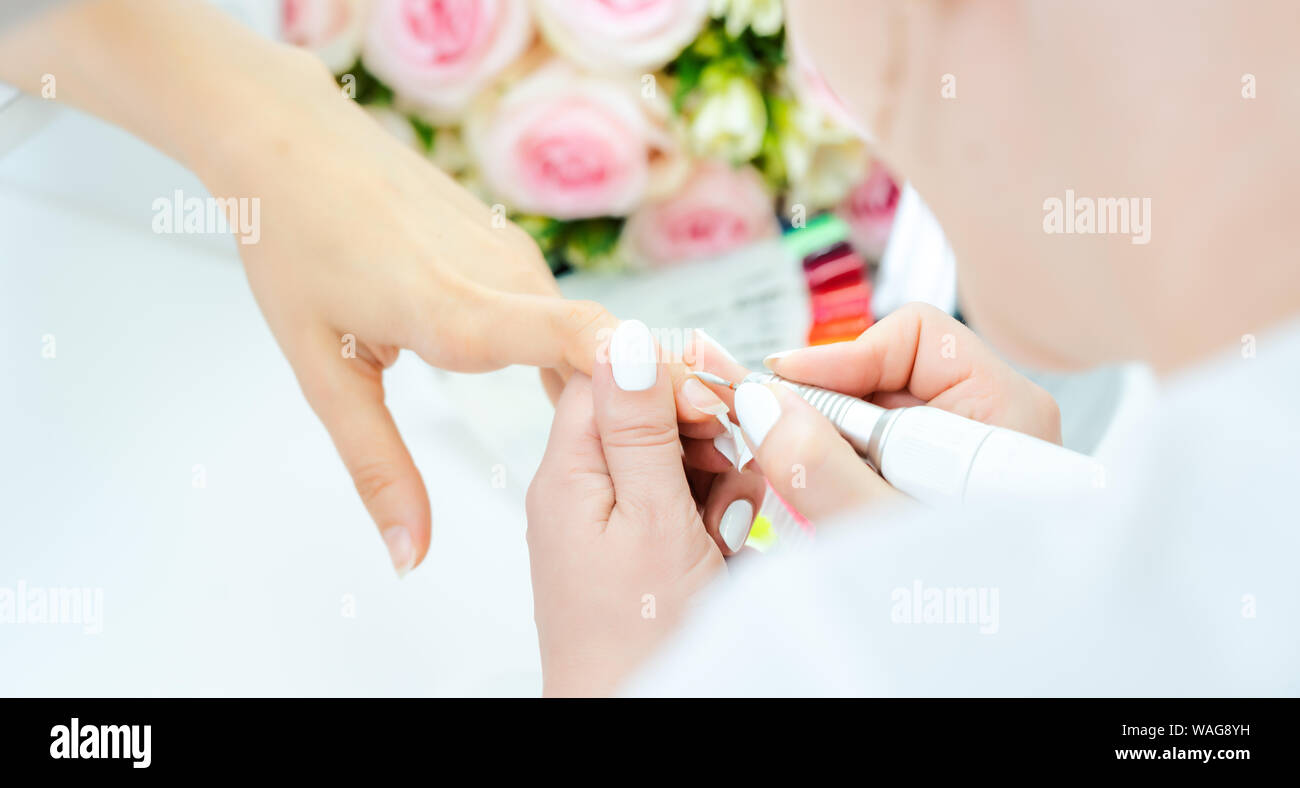 Le mani di un abile manicurist lavorando sulle unghie di una giovane donna Foto Stock