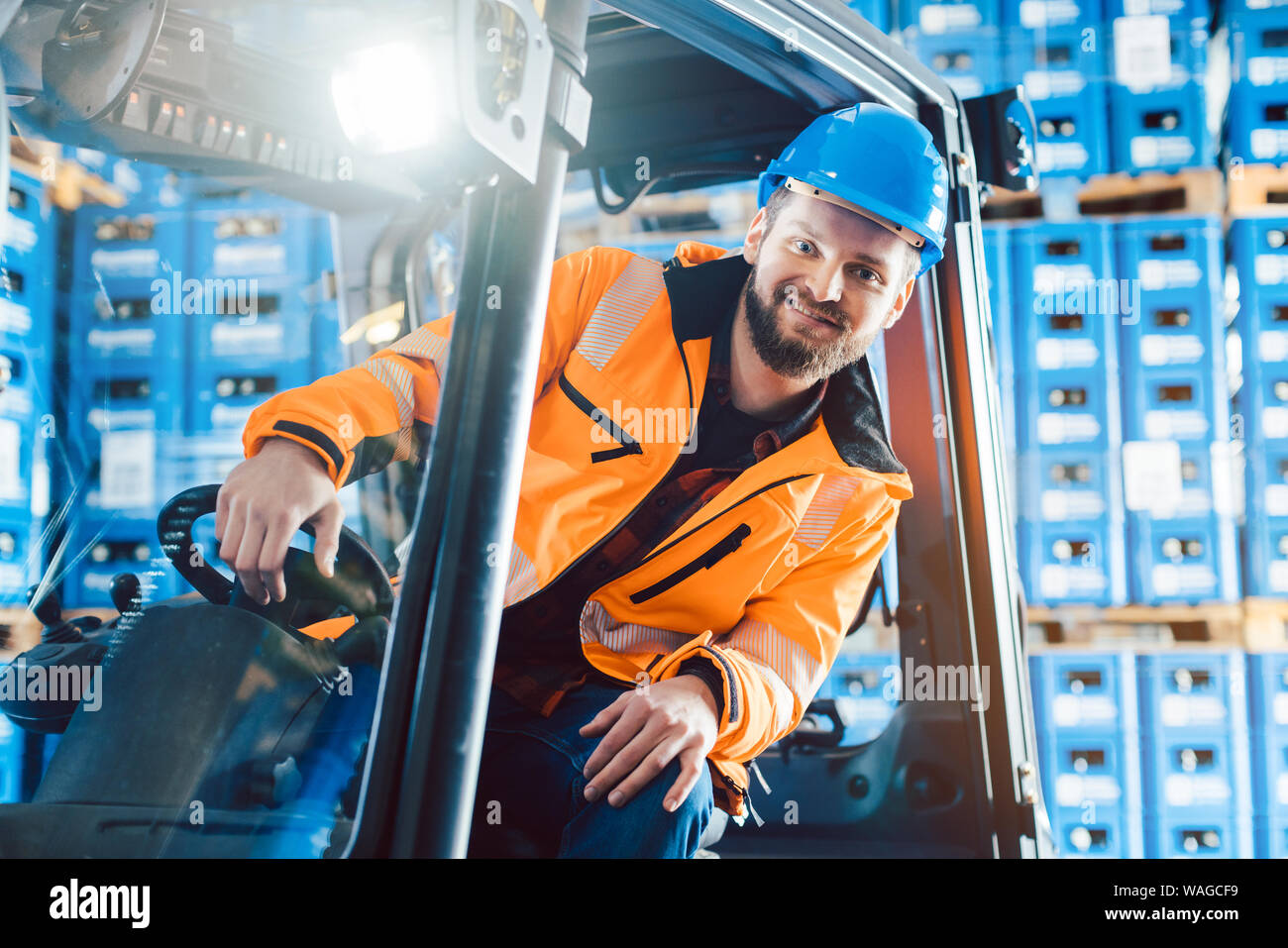 Lavoratore alla guida di un carrello elevatore a forche in logistica centro di consegna Foto Stock