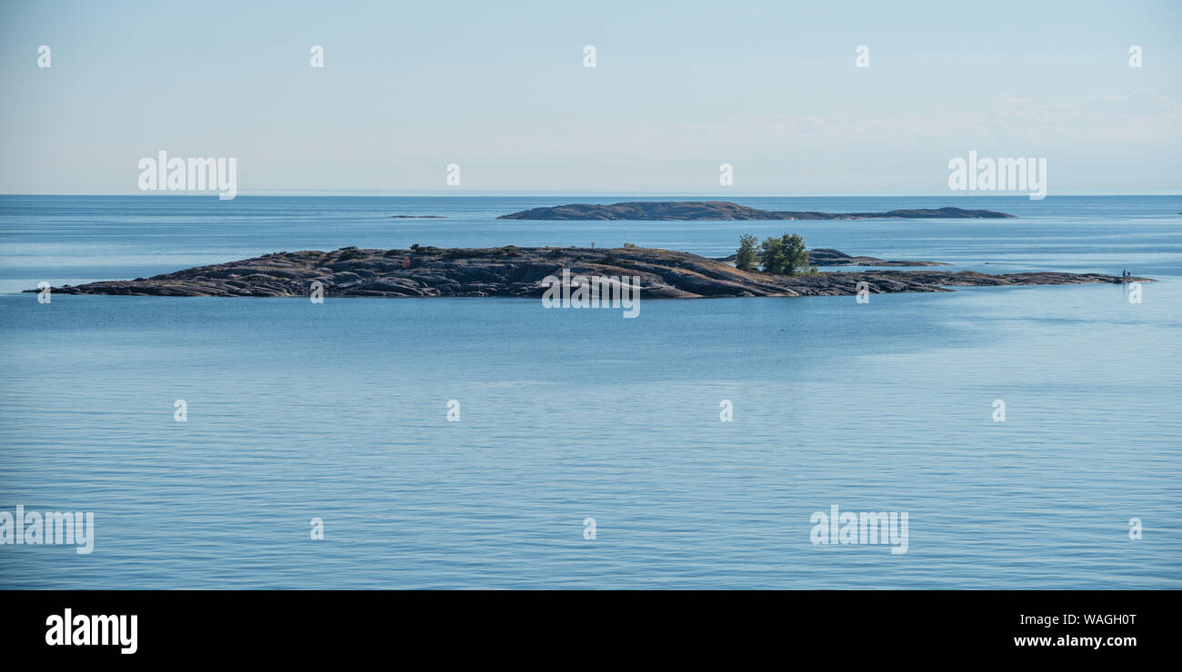 Estate scandinava in arcipelago toscano - molto bassi isolotti oblunga passando da acque blu del Mar Baltico. Cespugli verdi crescente dalle rocce, minuscoli uomini Foto Stock