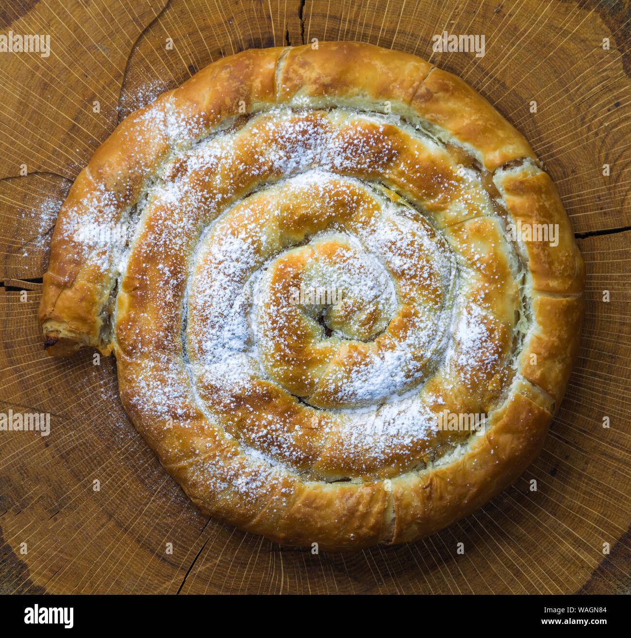 Round la torta di mele su una tavola di legno rustico sfondo. Organico in casa torta di mele con zucchero a velo o Burek. Vista superiore foto di gustosa torta di mele con lo zucchero. Foto Stock