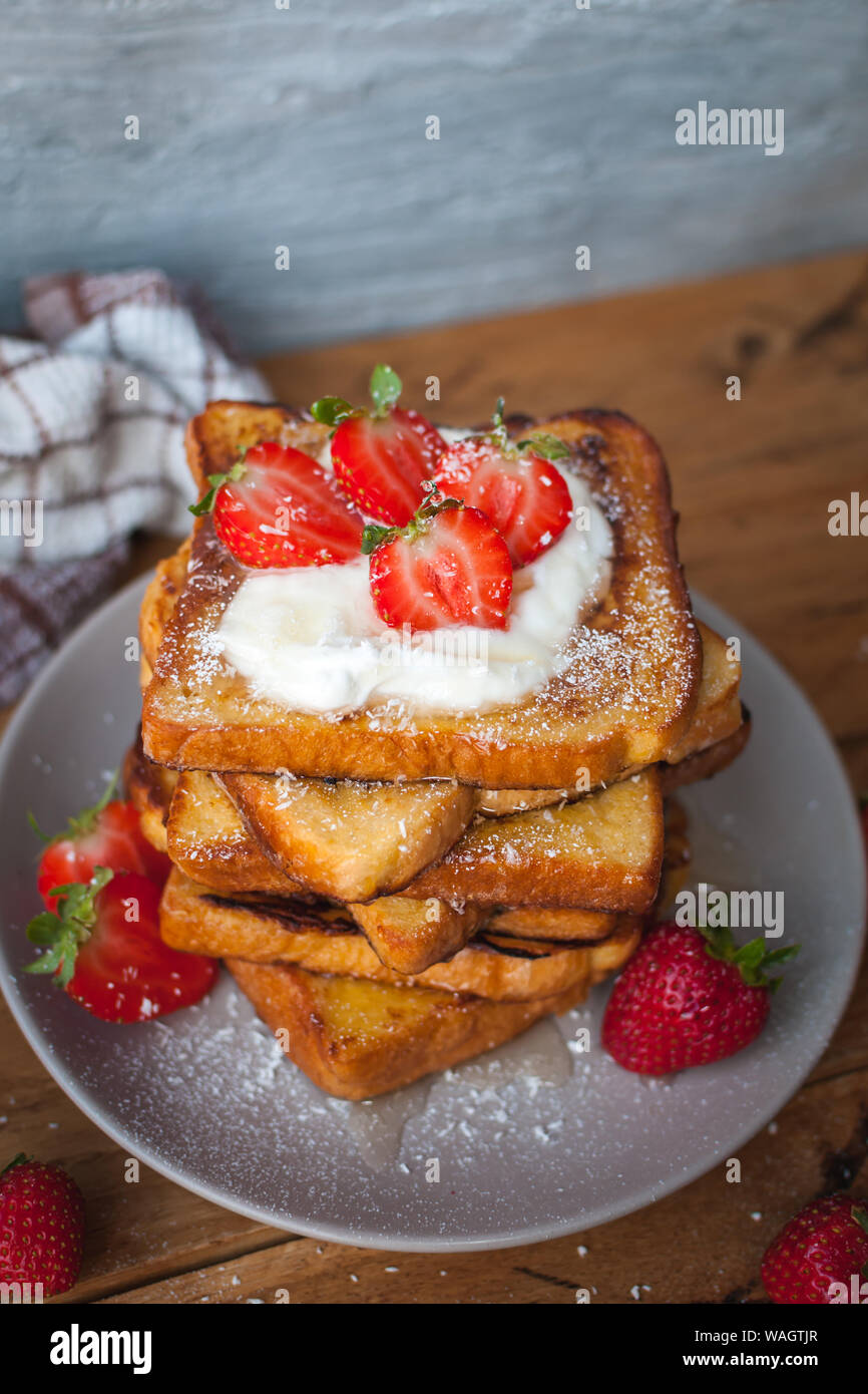 Toast alla francese con fragole fresche, filamenti di cocco e miele, su sfondo di legno Foto Stock