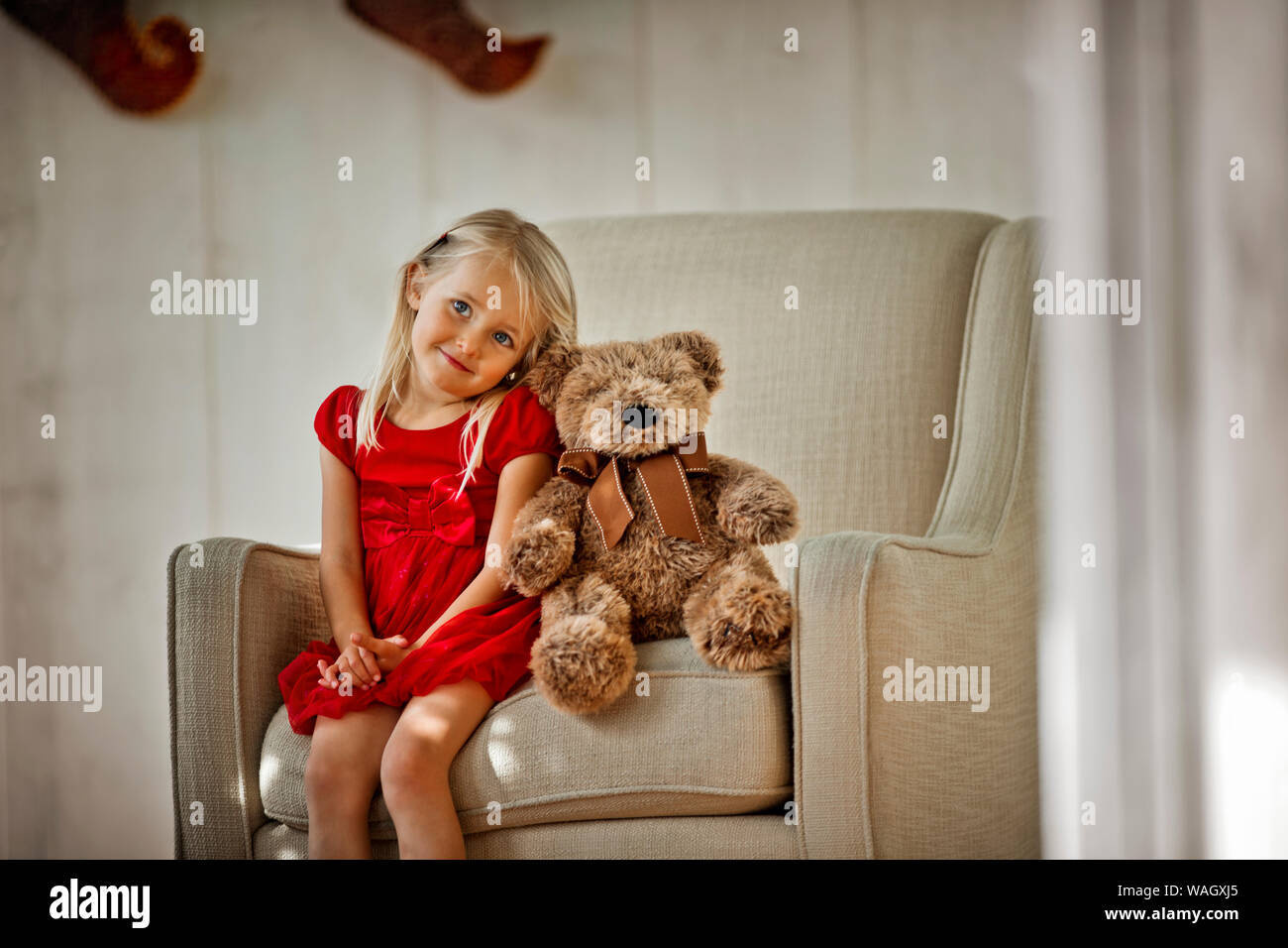 Giovane ragazza seduta su una poltrona con il suo orsacchiotto di peluche. Foto Stock