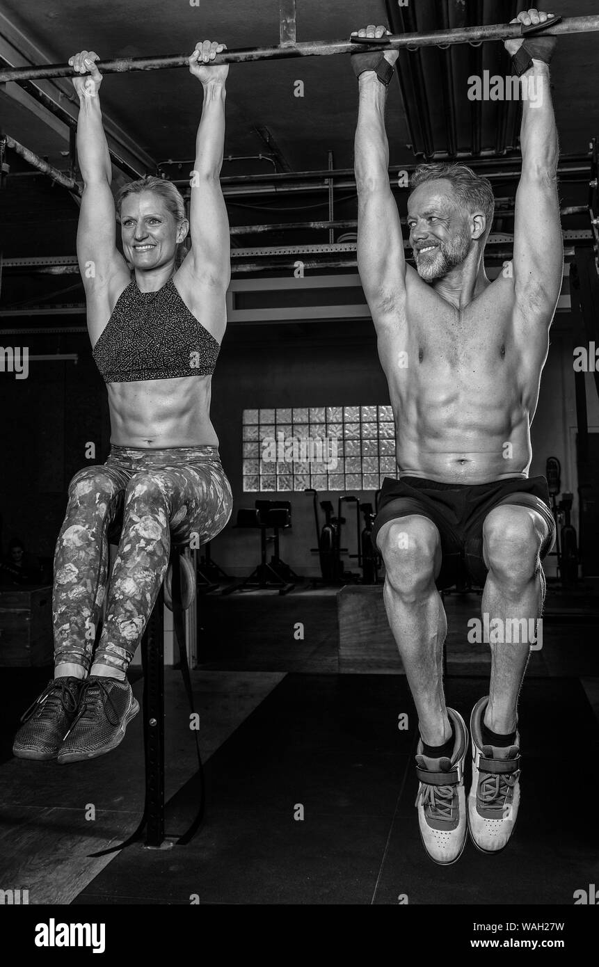Una bella coppia di mezza età sta facendo un allenamento di fitness insieme e divertirsi. Muscolare di vecchio uomo e donna stanno facendo del ginocchio si solleva. Foto Stock