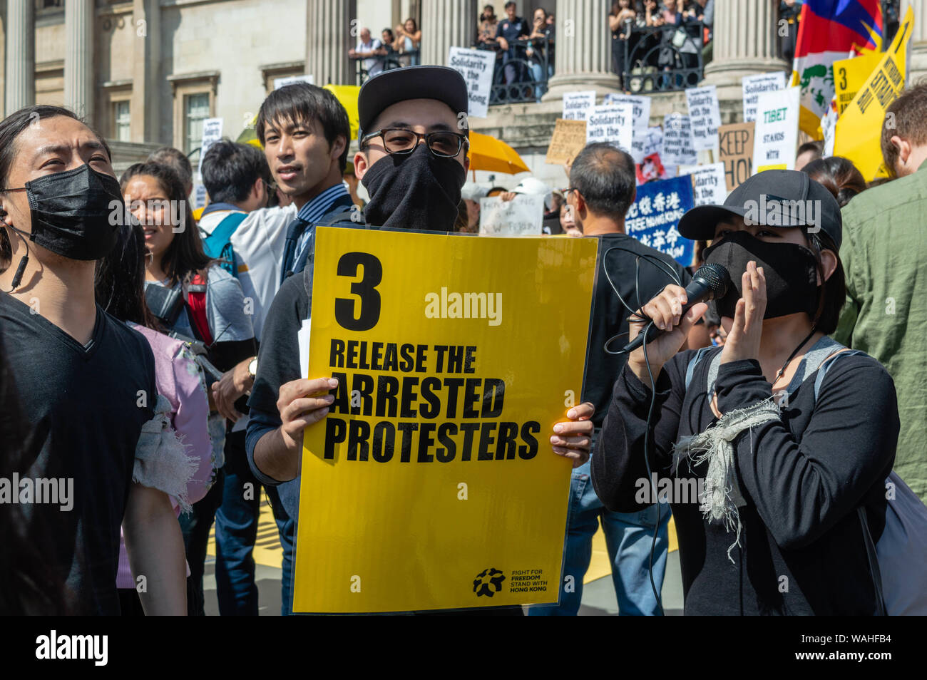 Maschio asiatici sostenitore del Regno Unito la solidarietà con Hong Kong rally tenendo su un banner che richiede che i dimostranti arrestati in Hong Kong essere rilasciato. Foto Stock