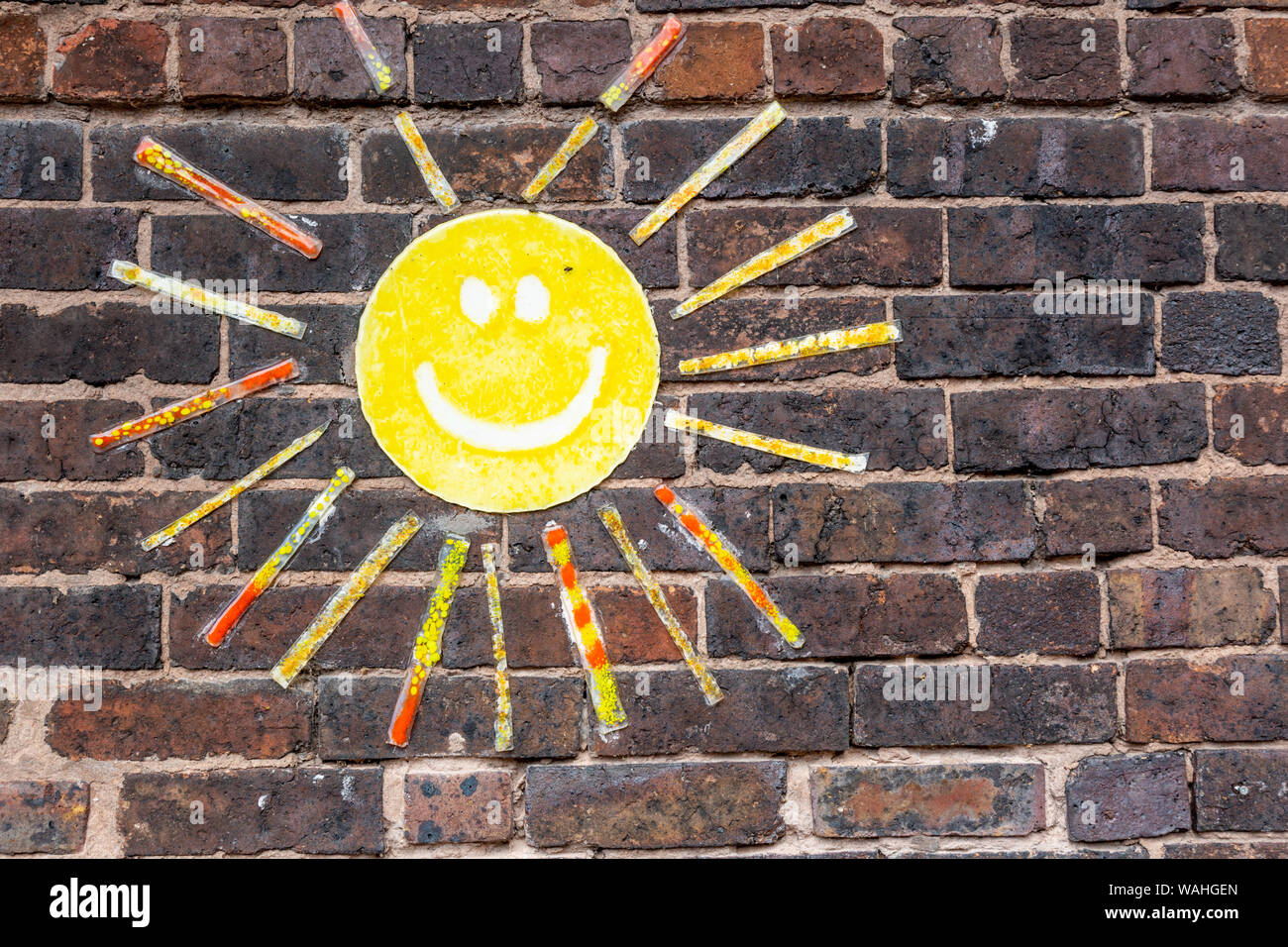 Sun infantili raffigurato su un vecchio muro di mattoni Foto Stock