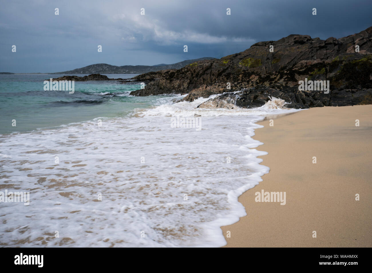 Unnamed spiaggia con le onde del mare e rocce nere sulla costa occidentale di Harris, isola di Lewis, Ebridi Esterne, Scotland, Regno Unito Foto Stock