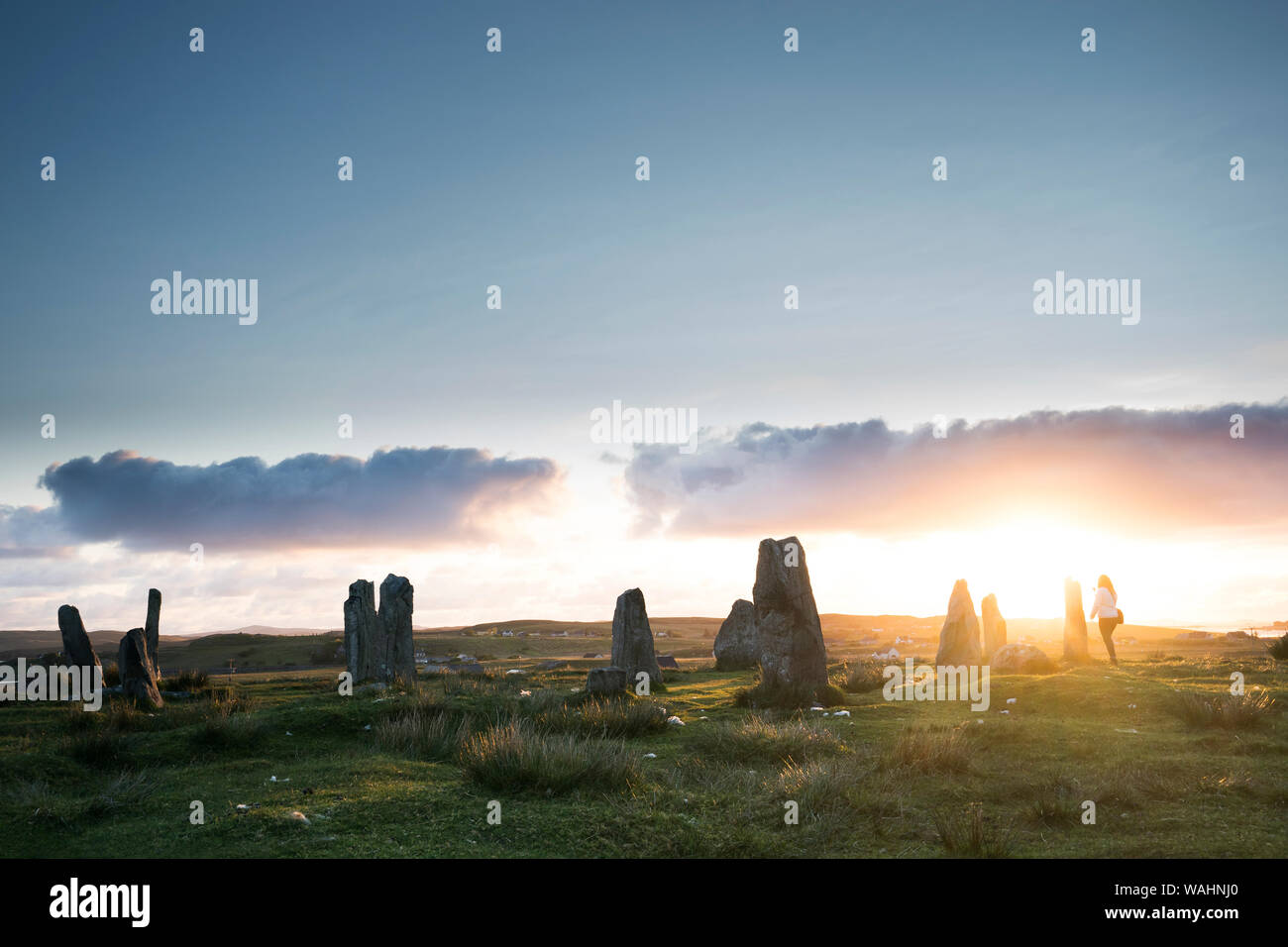Tourist si aggira intorno a breve le formazioni rocciose a pietre di Callanish III al tramonto, isola di Lewis, Ebridi Esterne, Scozia Foto Stock