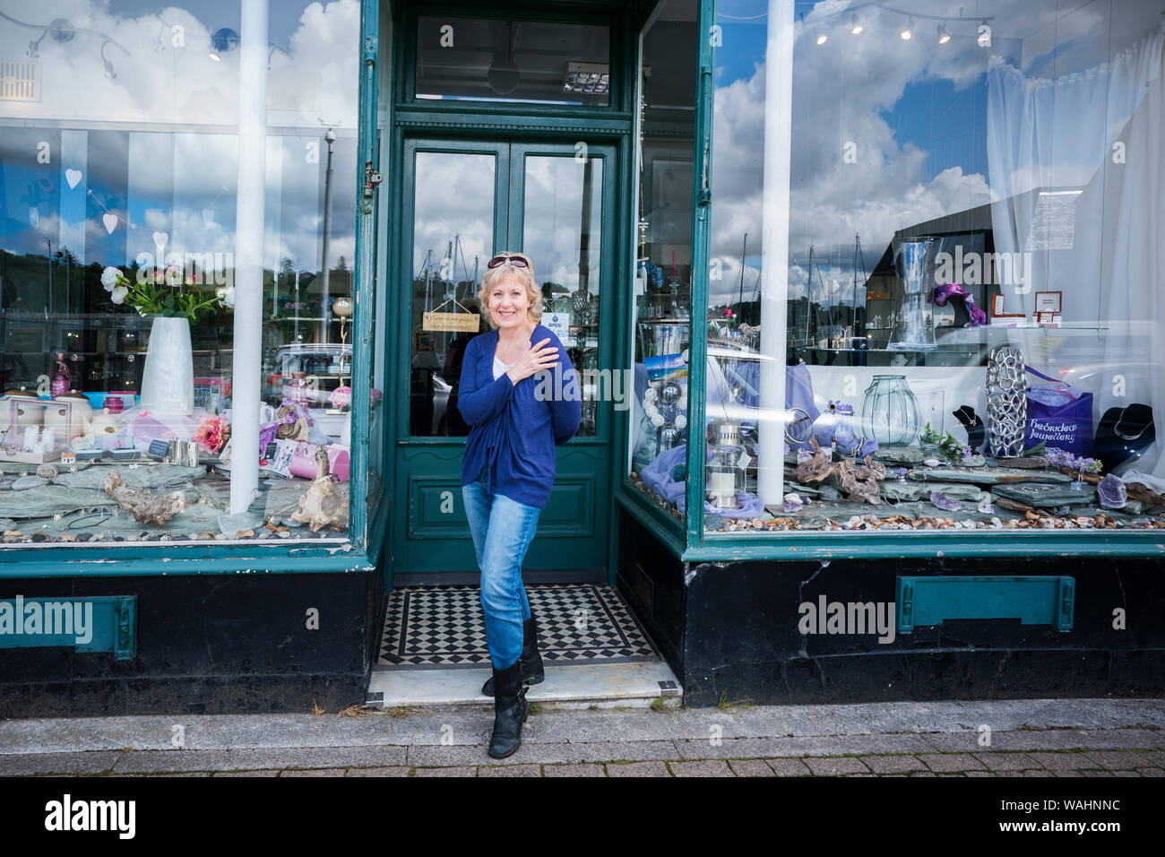 Felice donna bionda nel suo 50's mostra off il Silver Cerchio Celtico acquistati presso il negozio di gioielli a Stornoway, isola di Lewis, Ebridi Esterne, Regno Unito, Europa Foto Stock