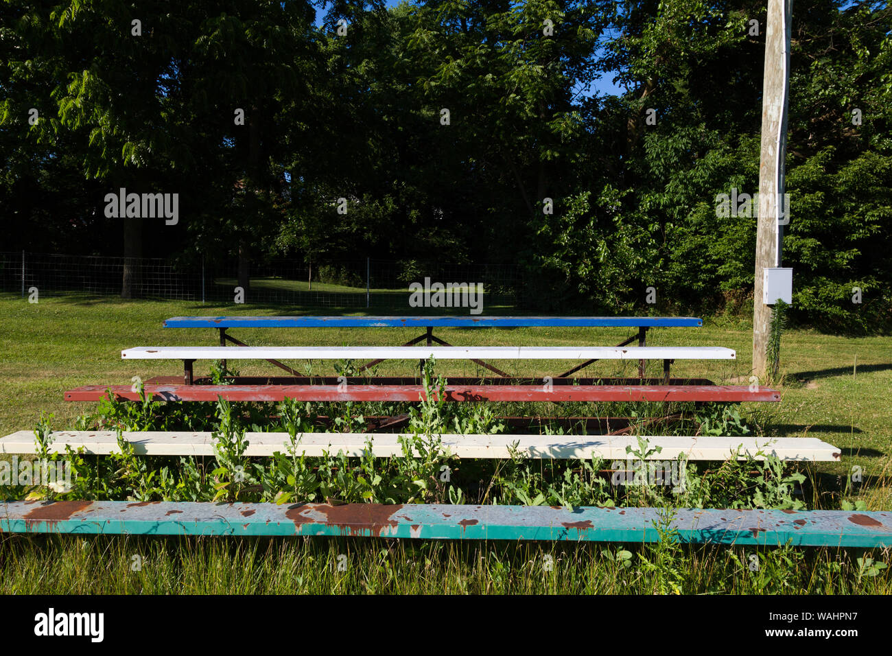 I bleachers surcresciuti abbandonati siedono vicino al treeline al Roanoke Park a Roanoke, Indiana, Stati Uniti. Foto Stock