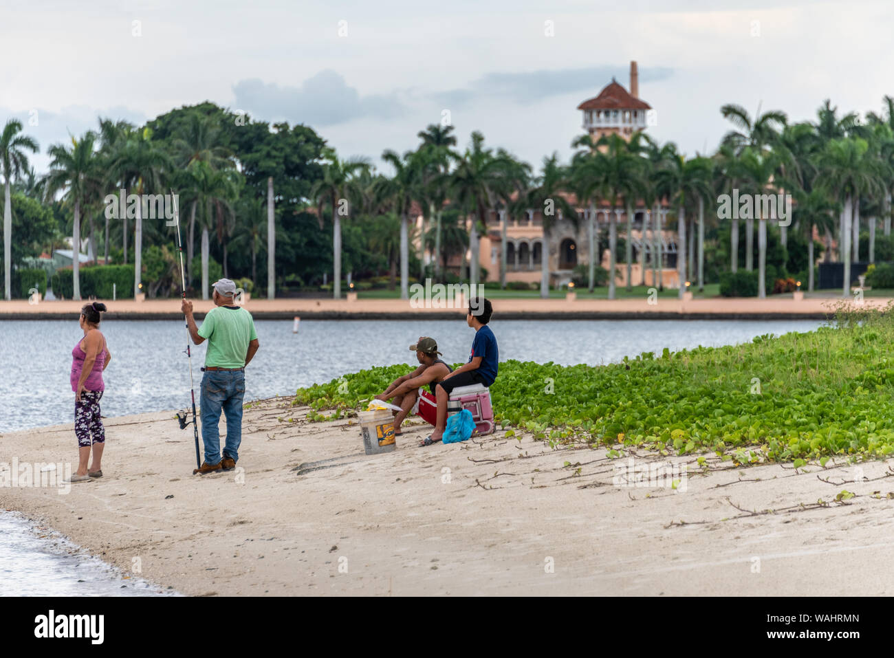 Famiglia di origine ispanica la pesca da un'isola nel lago vale la pena di laguna di fronte al presidente Donald Trump's Palm Beach mansion station wagon, Mar-a-Lago. (USA) Foto Stock