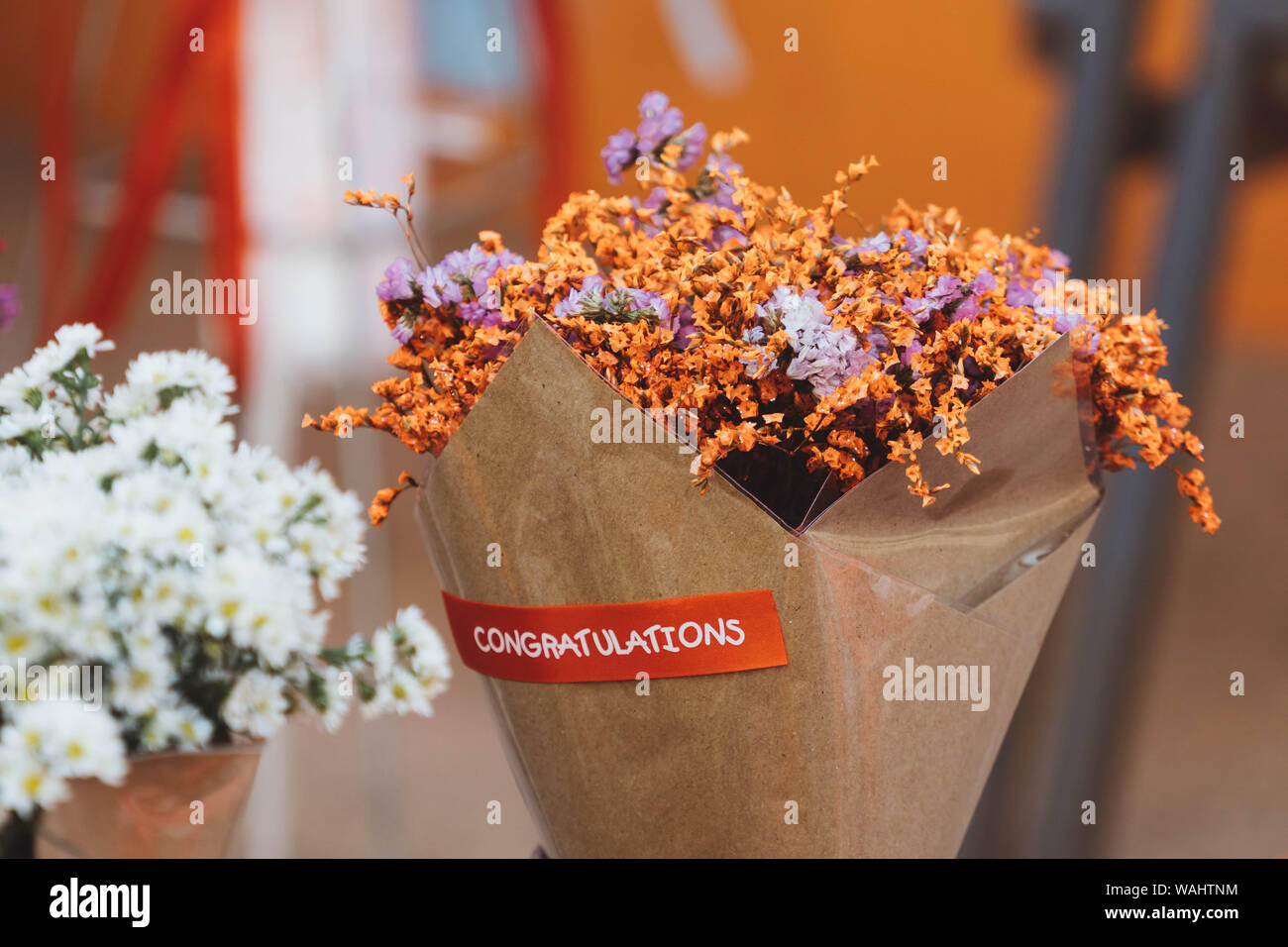 Bouquet di essiccati Fiori arancione avvolto in carta con etichetta di saluti Foto Stock