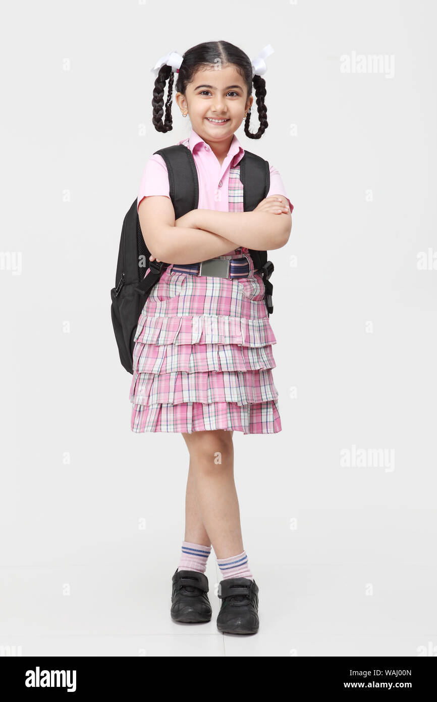 Schoolgirl in piedi con zaino e sorridente Foto Stock