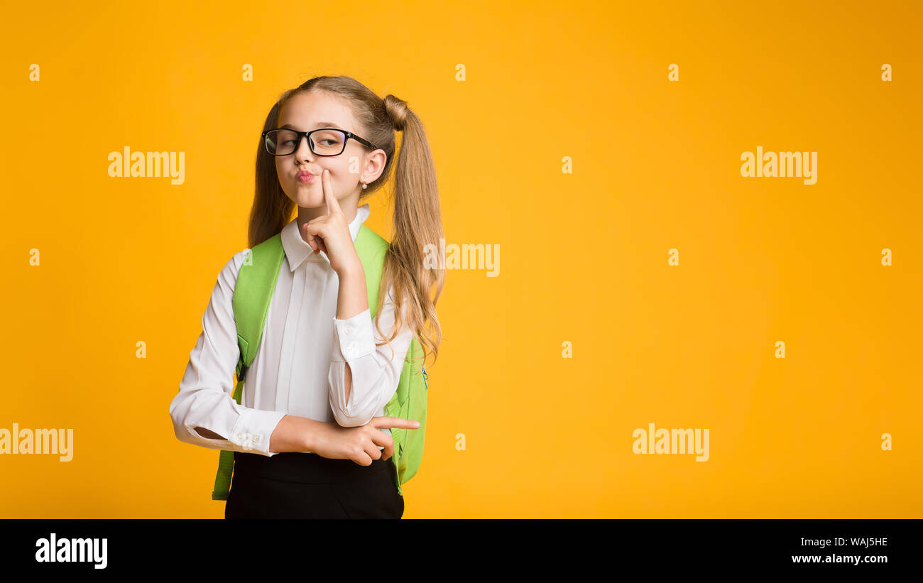 Funny Schoolgirl posa essendo altero su sfondo giallo Foto Stock